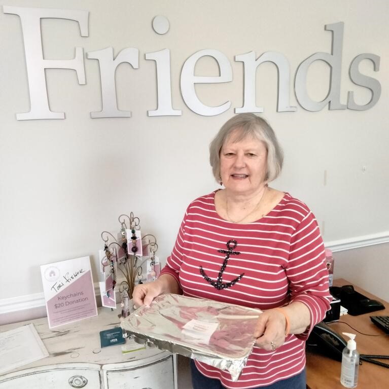 a woman holding a meal she prepared and is donating to those experiencing homelessness.