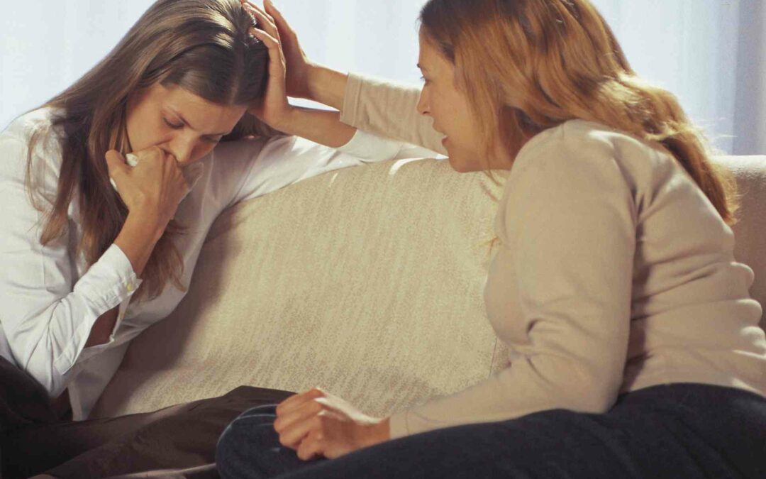 Two women on a couch using trauma-informed language.